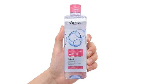 nuoc_tay_trang_loreal_cho_da_kho_micellar_water_moisturizing_b8793e3e65fc4587a472e9e4c4eebb7d_grande Một tay cầm chai nước tẩy trang micellar màu hồng trắng, nhãn hiệu và thông tin sản phẩm được in trên nhãn.
