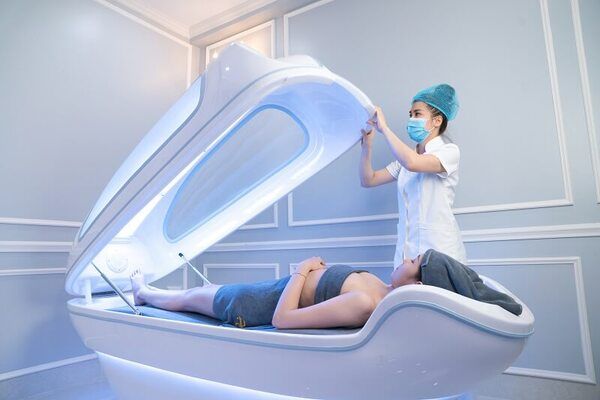 Người mặc đồng phục y tế mở nắp thiết bị chăm sóc sức khỏe cho khách hàng nằm bên trong trong phòng hiện đại.