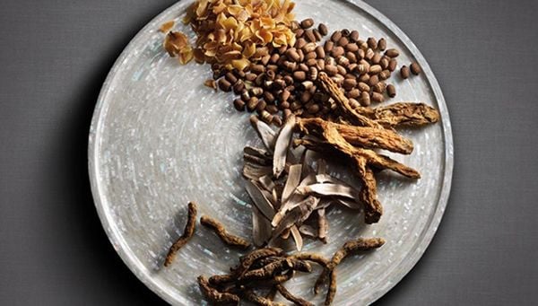 Đĩa tr&ograve;n chứa nhiều loại thảo mộc v&agrave; hạt kh&ocirc;, sắp xếp gọn g&agrave;ng tr&ecirc;n bề mặt tối giản.