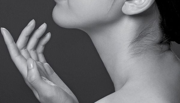 Người phụ nữ nghi&ecirc;ng đầu, tay chạm nhẹ l&ecirc;n cằm, nền đen trắng.