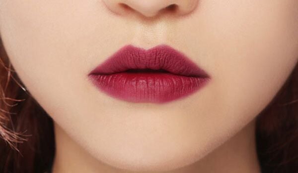 Cận cảnh đôi môi tô son màu đỏ đậm trên nền da sáng.