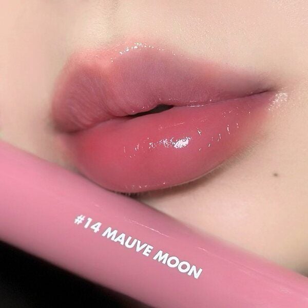son_hong_tim_mauve_co_do_bong_nhe__tao_hieu_ung_cang_muot_cho_doi_moi_a60c691e49d6439cbd74b1604c3f27cf_grande Đôi môi được tô son bóng màu hồng, cầm một thỏi son có ghi "#14 Mauve Moon".