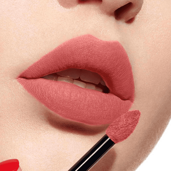 Cận cảnh môi đang được tô son màu hồng bằng cọ trang điểm.