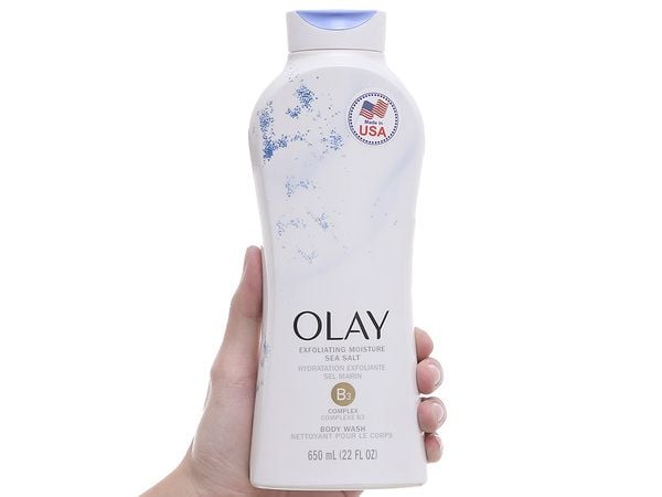 sua_tam_tay_te_bao_chet_diu_nhe_olay_body_wash_3a03df821d0a4a4a85cd2b4cdf2431d3_grande Chai sữa tắm Olay màu trắng, nhãn hiệu Exfoliating Moisture Sea Salt, dung tích 650 ml, cầm trên tay.