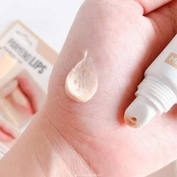 Một giọt kem dưỡng được lấy từ tu&yacute;p, đặt tr&ecirc;n l&ograve;ng b&agrave;n tay, với hộp sản phẩm mờ ph&iacute;a sau.