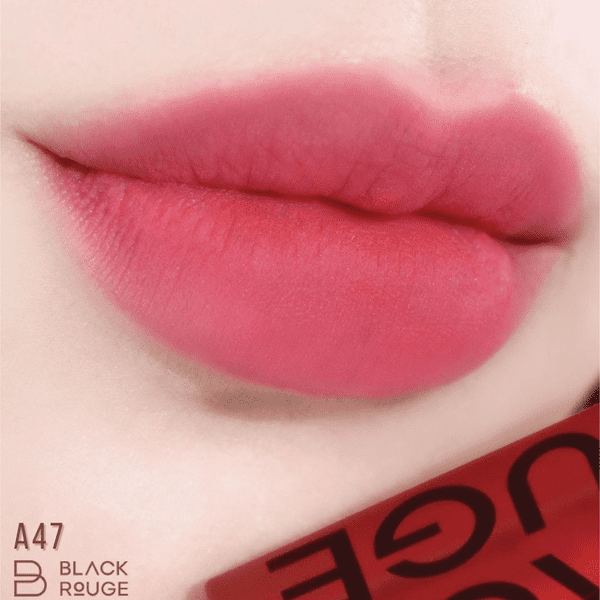 Đôi môi được tô son màu hồng đậm, bên dưới có hộp son có chữ "Black Rouge A47".