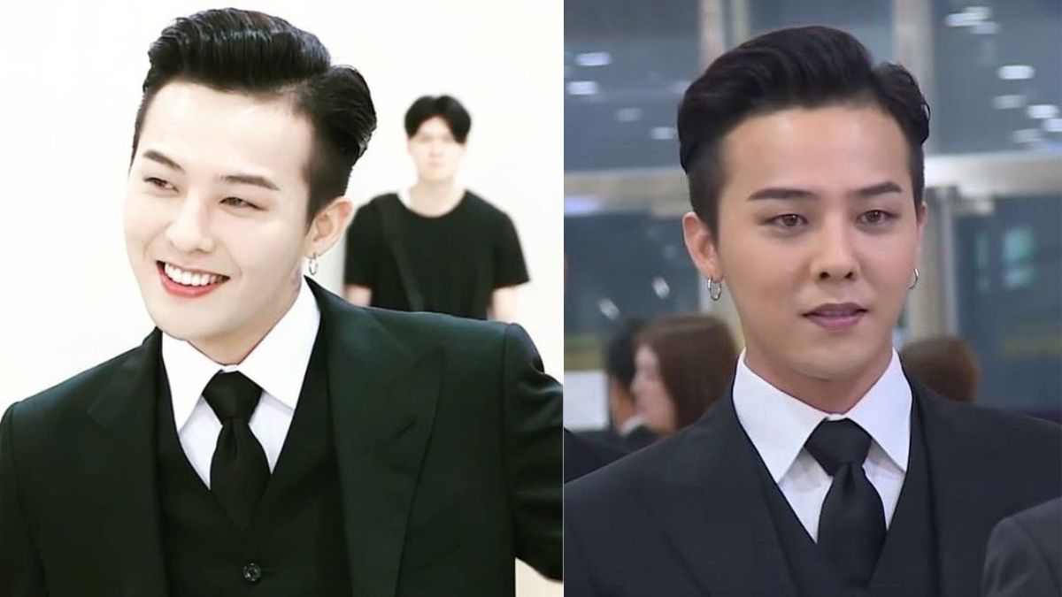 toc-g-dragon-7 Hai người đàn ông mặc vest đen, một người đang cười, nền có người mờ nhòe đứng phía sau.