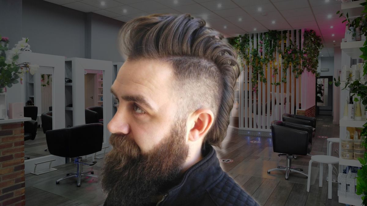 toc-mohawk-12 Người đàn ông với kiểu tóc undercut và râu rậm trong tiệm cắt tóc hiện đại, có ghế và gương.