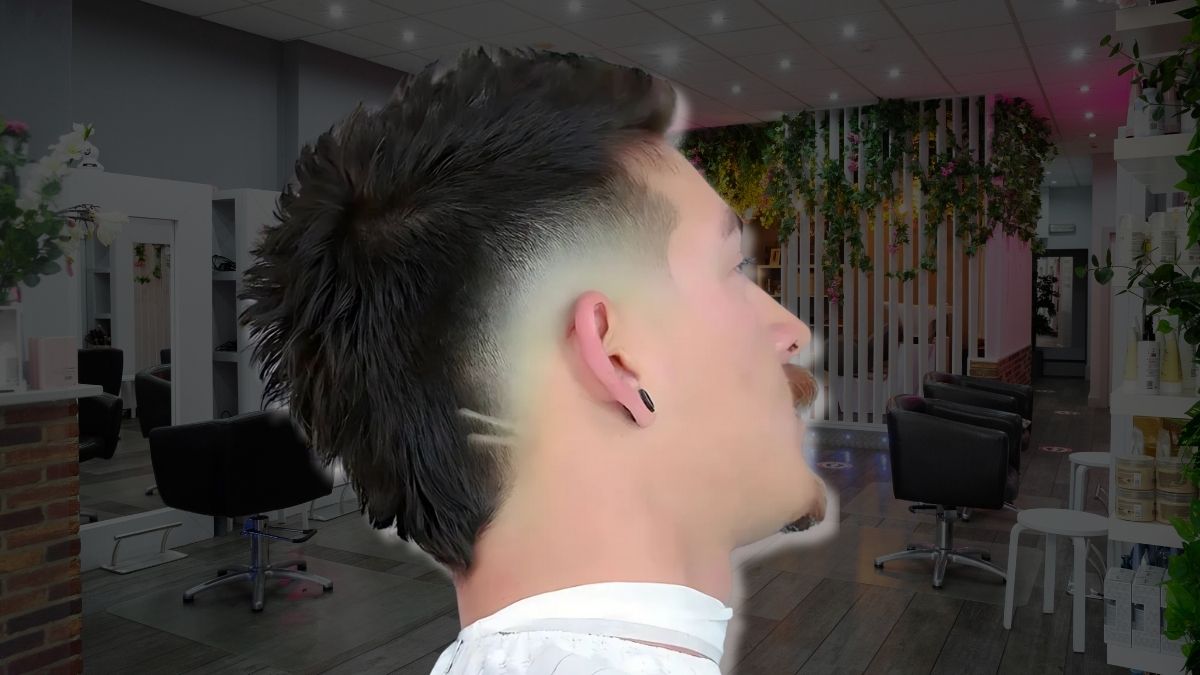 toc-mohawk-3 Người với kiểu tóc mullet trong tiệm cắt tóc, nền là nội thất hiện đại với cây xanh trang trí.