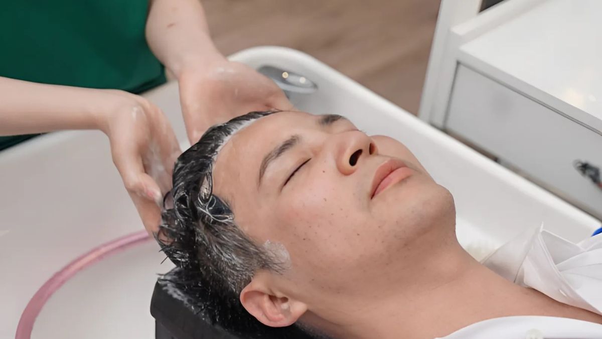 toc-quan-ap-4 Người đang nằm thư giãn khi được gội đầu tại tiệm làm tóc, với bọt xà phòng trên tóc.