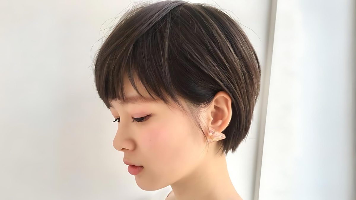 Người có mái tóc ngắn, màu tối, đeo hoa tai, nhìn nghiêng trong không gian ánh sáng tự nhiên.