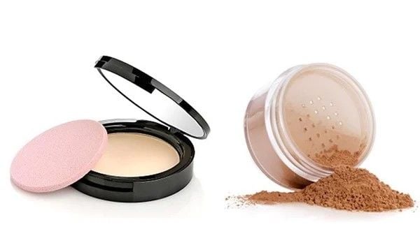 Hộp phấn nén mở nắp và hộp phấn bột đổ ra ngoài, kèm miếng bông trang điểm màu hồng.