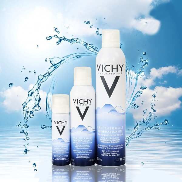 Ba chai xịt khoáng với nhãn hiệu, đặt trước nền nước và bầu trời xanh.